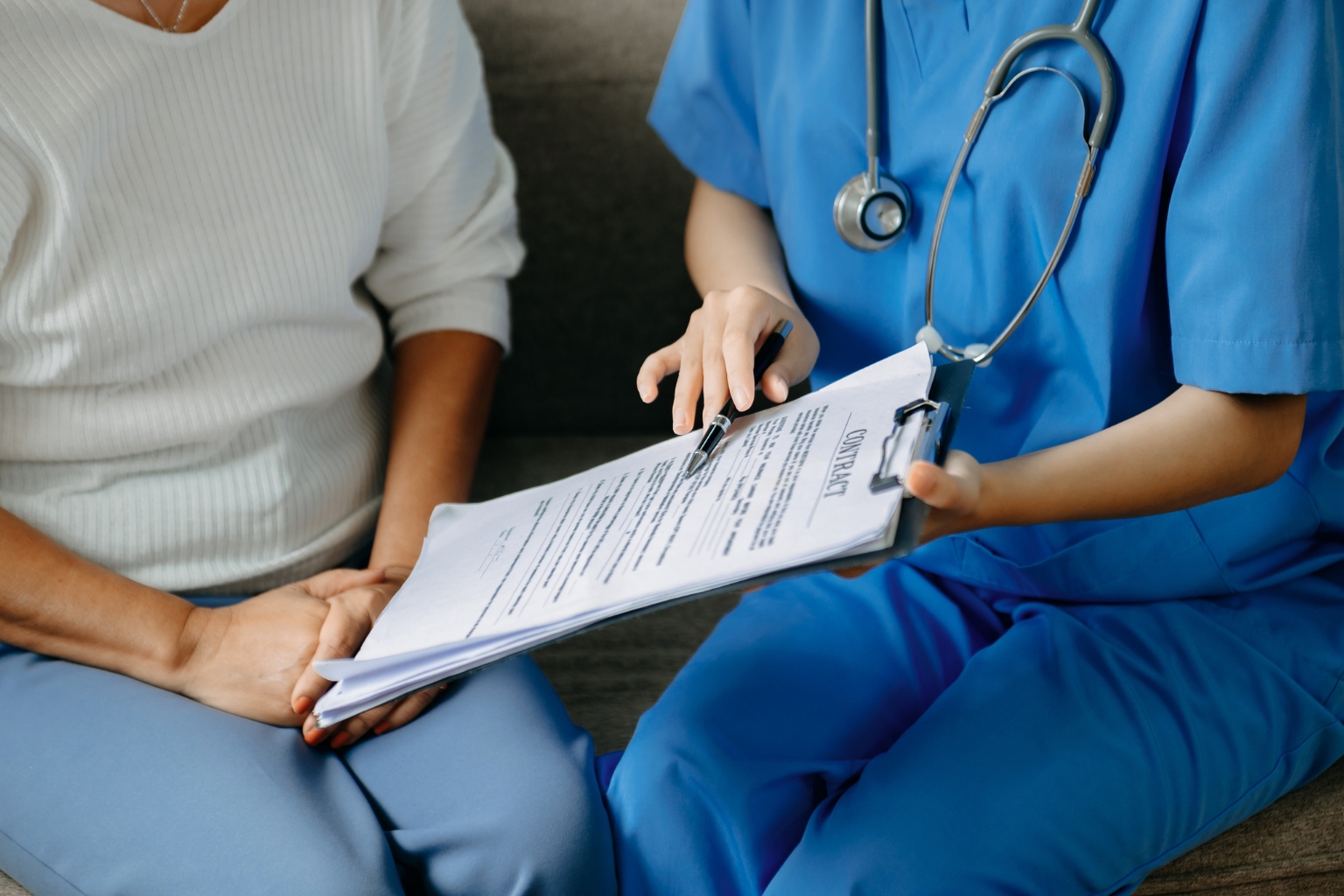 Infirmière présentant un formulaire de consentement aux soins à un patient assis à ses côtés