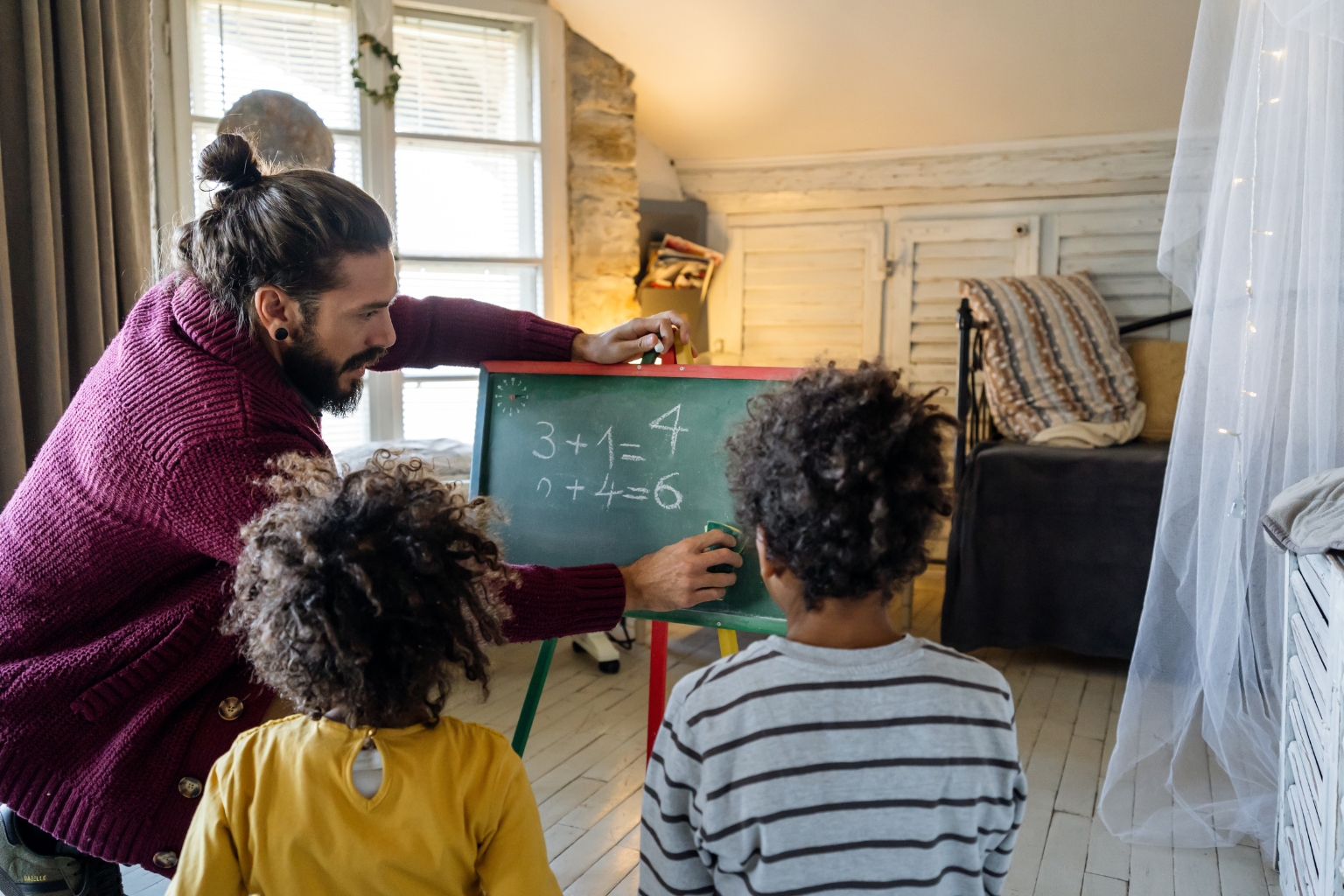 Parent faisant de l'enseignement à la maison avec ses deux enfants devant un tableau noir