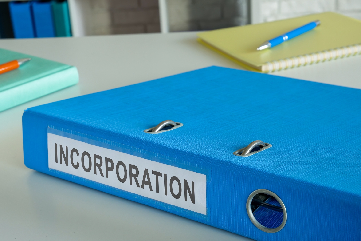 Classeur bleu étiqueté Incorporation sur un bureau avec des documents administratifs liés à l'incorporation d'une entreprise