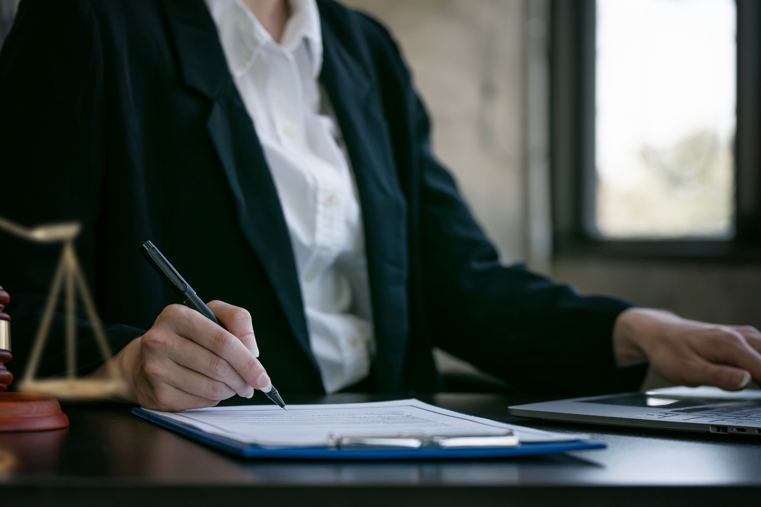 Juriste signant un document officiel, illustrant le traitement d’une infraction criminelle et pénale.