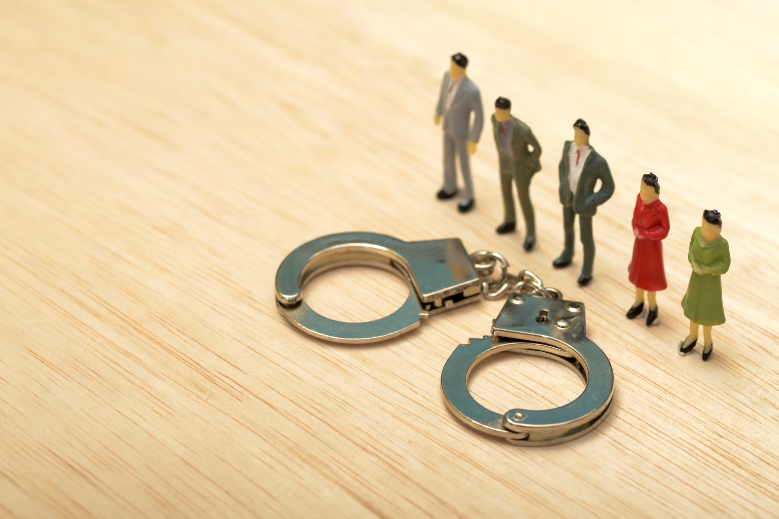 Figurines représentant des personnes alignées devant des menottes, illustrant la notion de mens rea et la responsabilité criminelle.